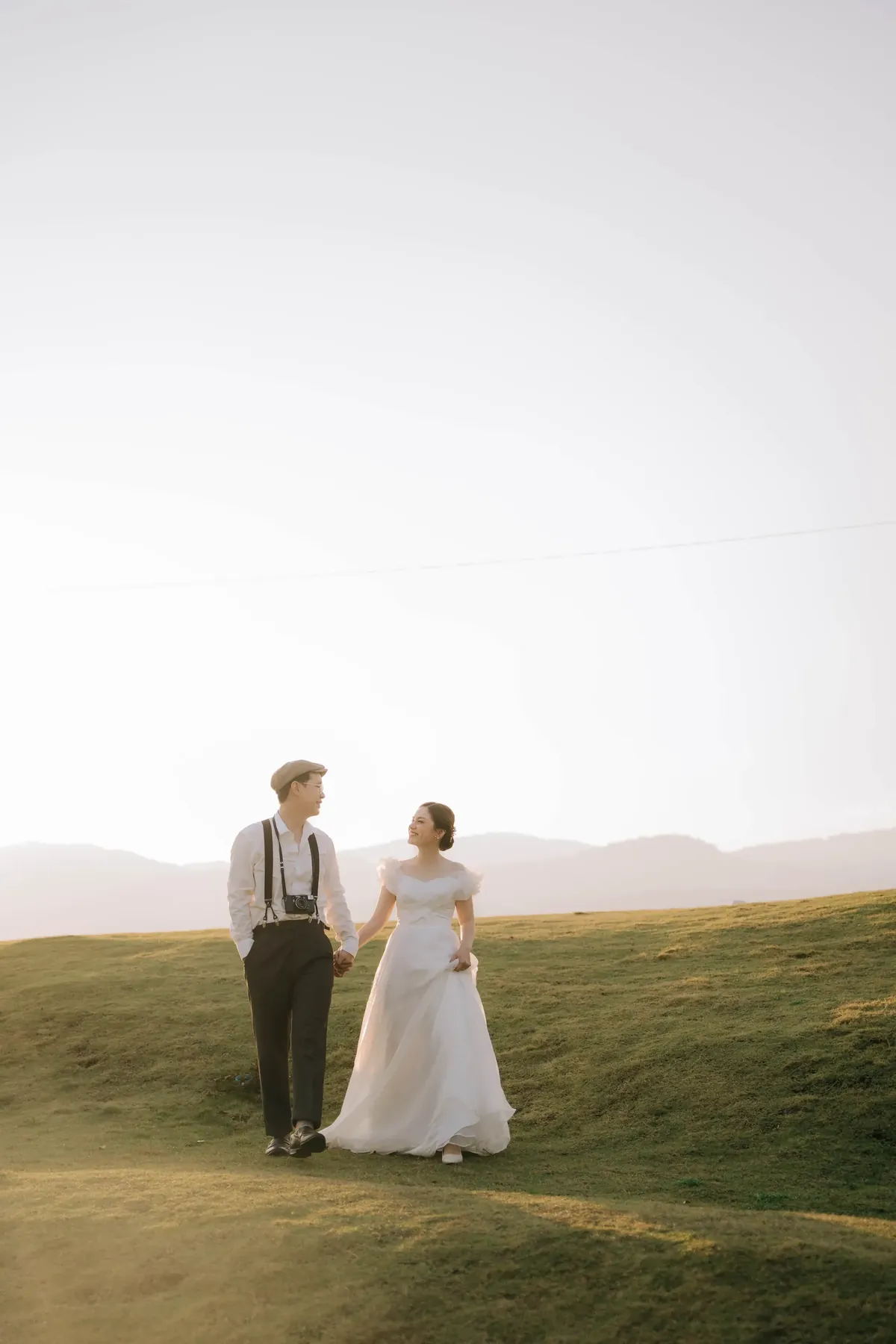 Som and Toon walking hand in hand on a hillside at sunset